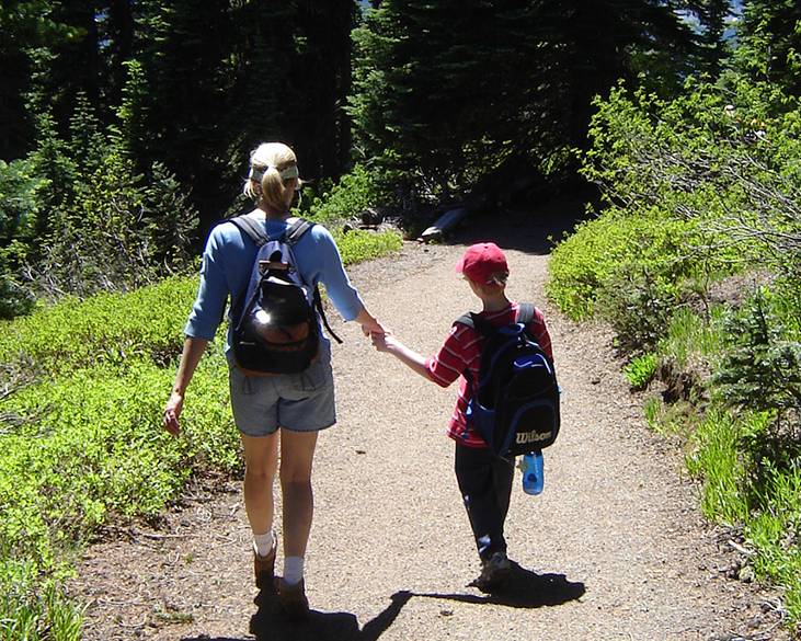 Woman and child walking on a trail on a sunny day. 